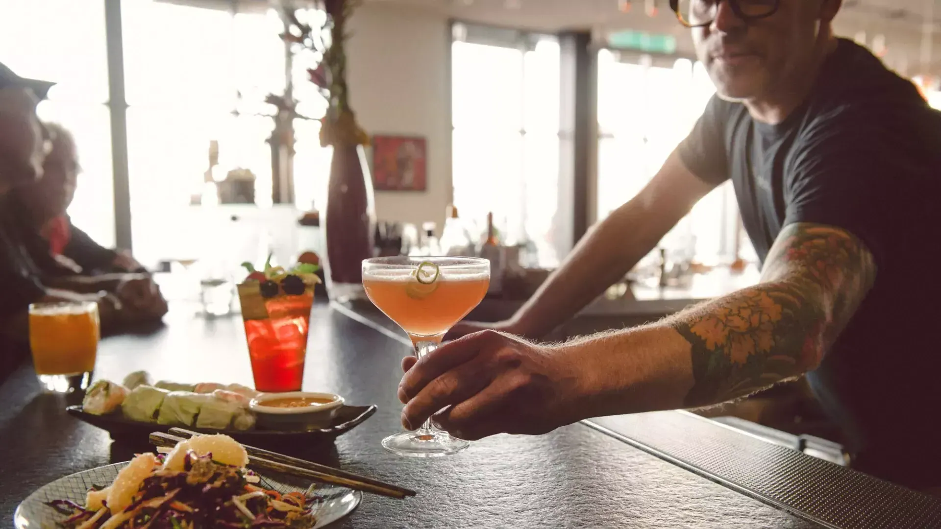 A bartender serves a patron a cocktail at a bar 在贝博体彩app.