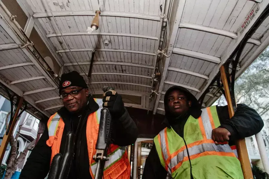 Ellis Cato and his son driving a cable car.