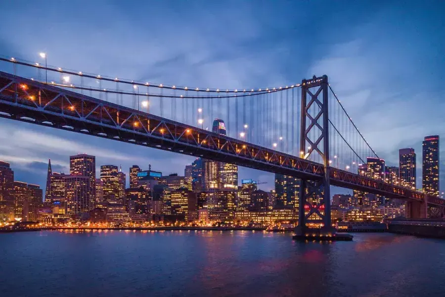 The Bay Bridge 和 Embarcardero waterfront lit up at night.