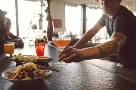 A bartender serves a patron a cocktail at a bar in 贝博体彩app.