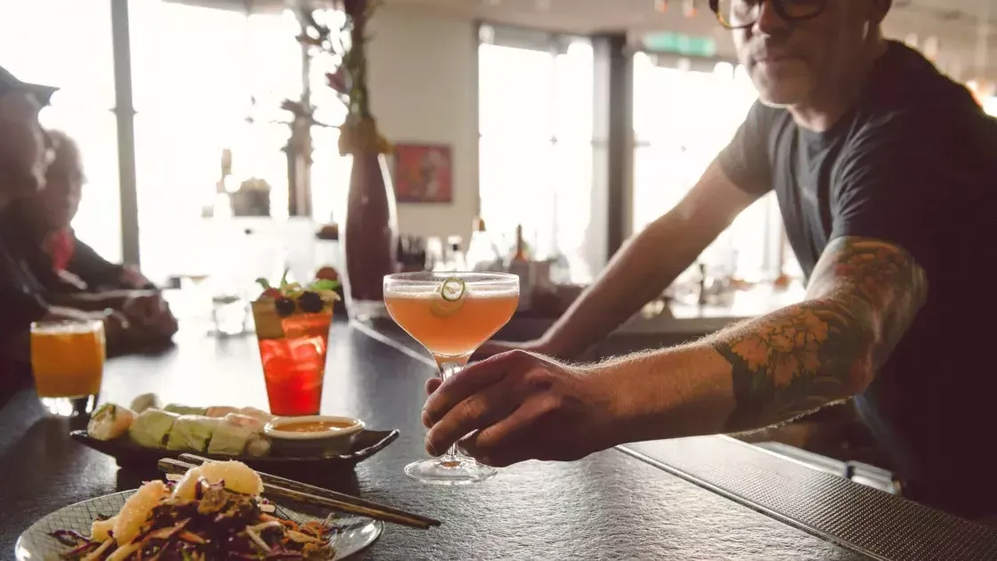 A bartender serves A patron A cocktail at A bar in San Francisco.